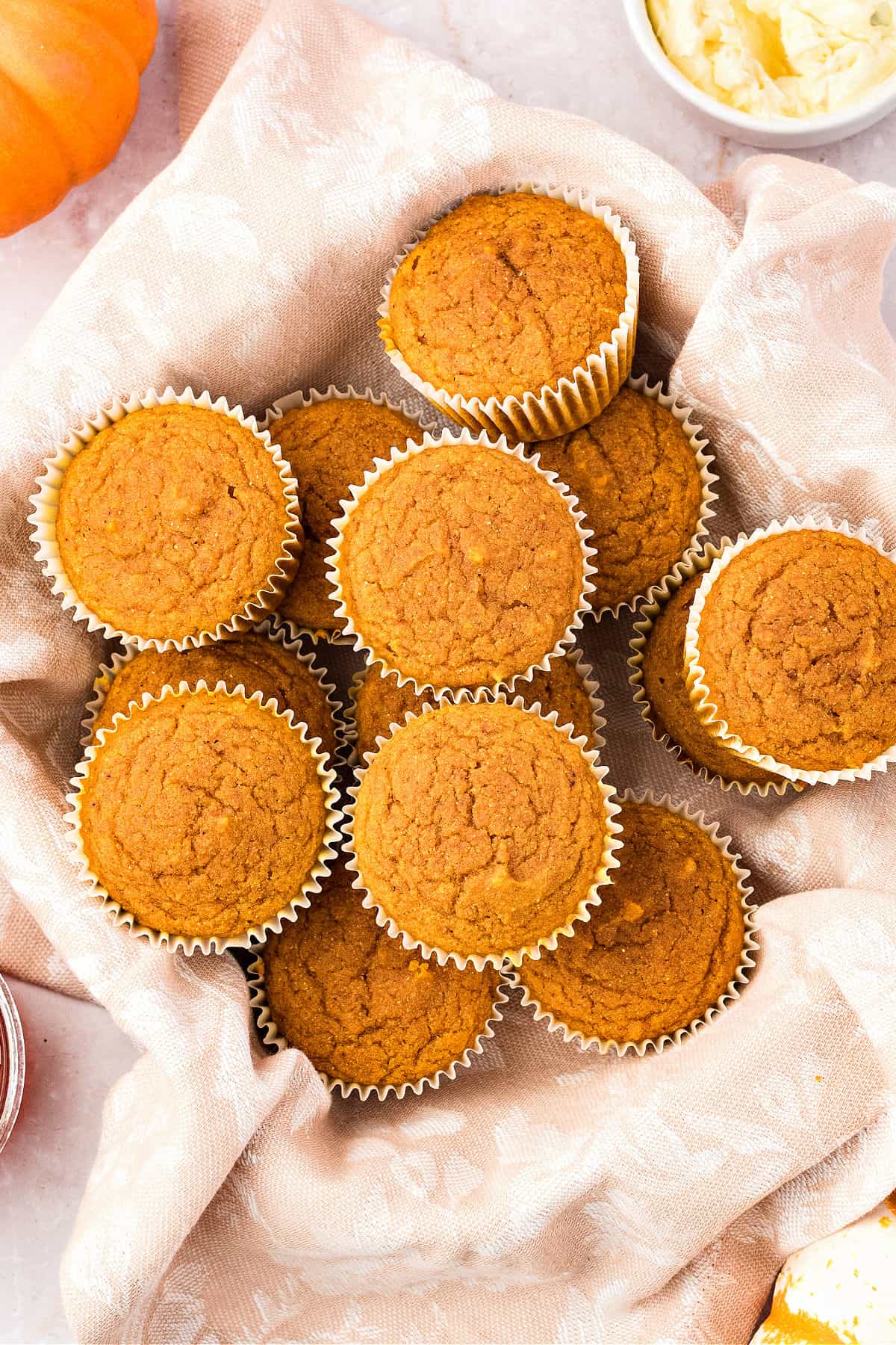 Pile of pumpkin cornbread muffins on whitish towel. Top view.