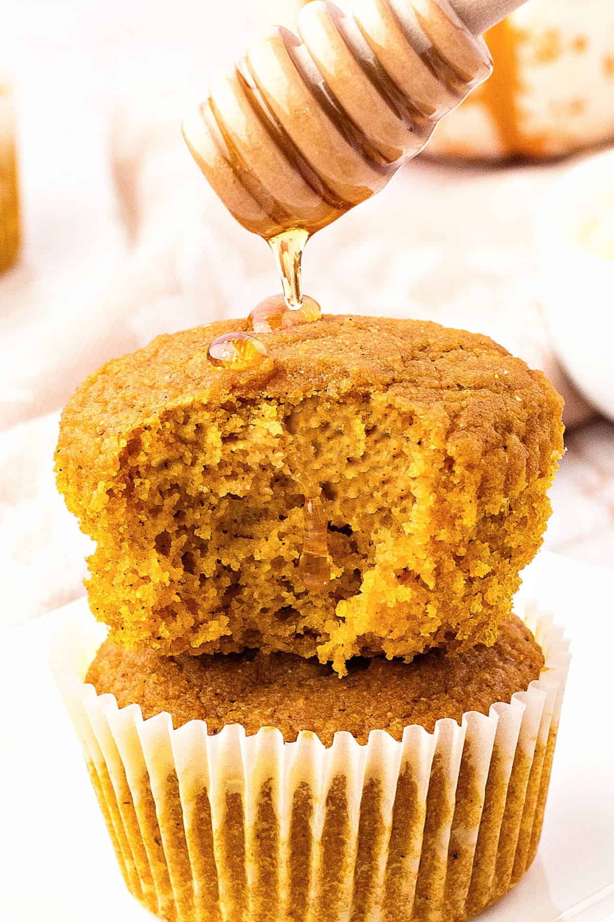 Drizzling honey on bitten cornbread pumpkin muffin.