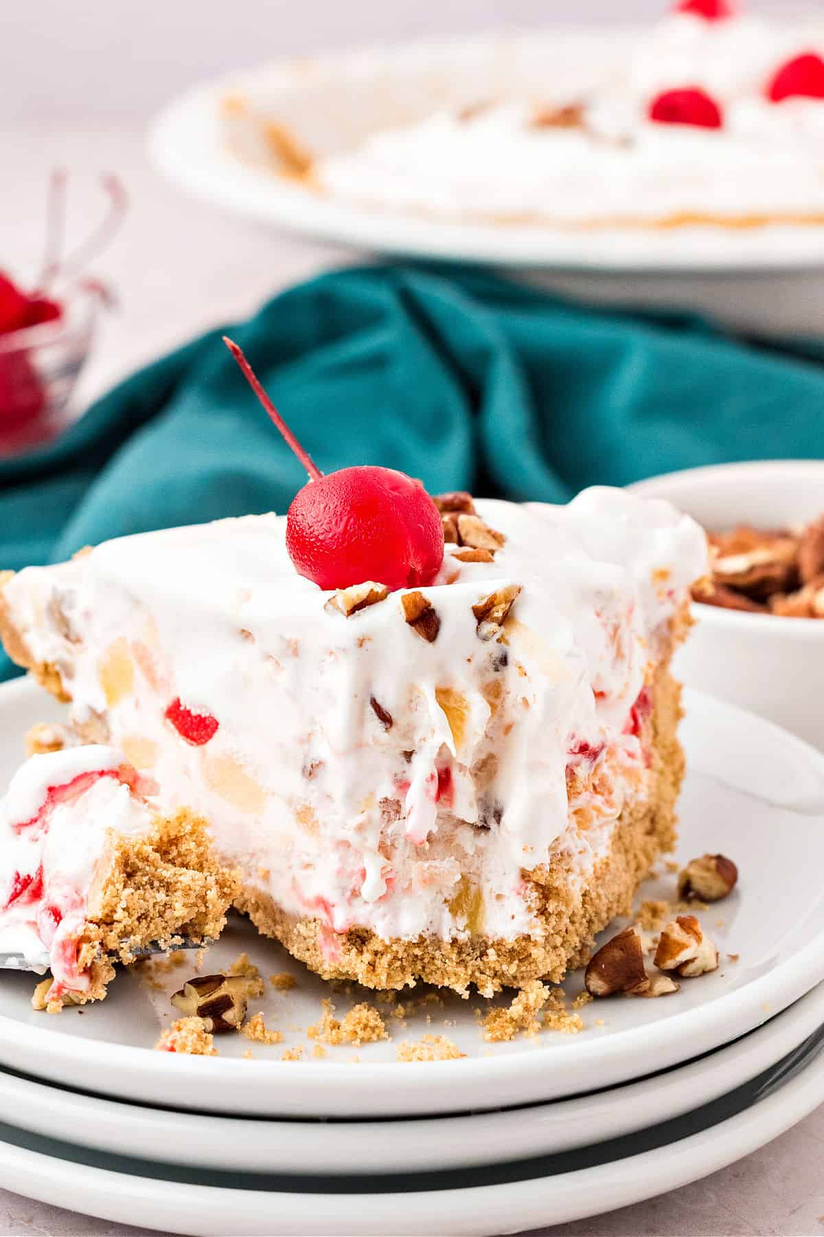 Forked slice of fruit cream pie on a white plate. Teal cloth and pie pan in the background.
