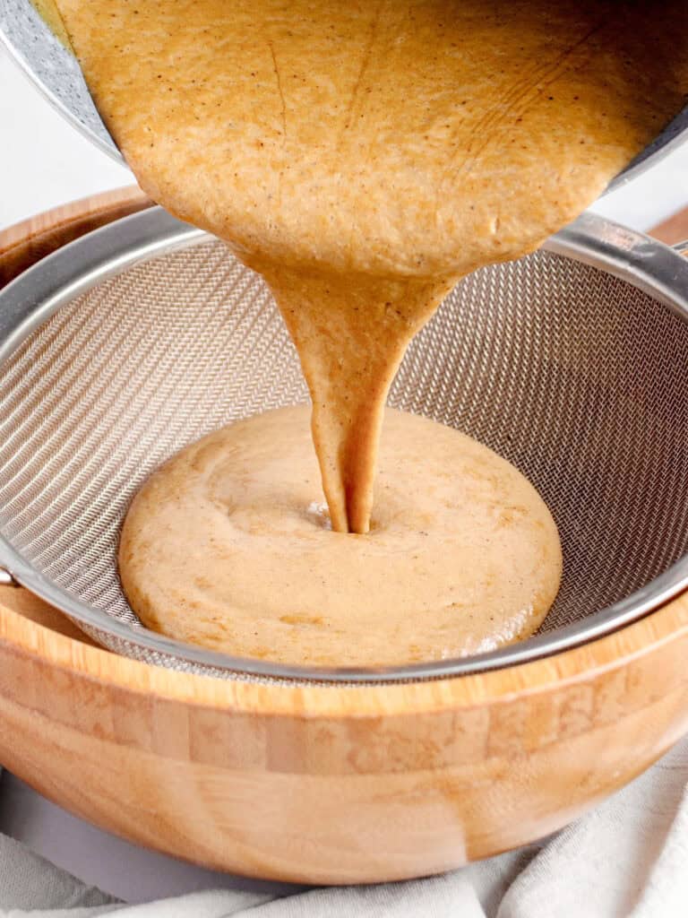 Sieving butterscotch mixture onto wooden bowl.