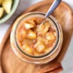 Jar of apple pie filling and topping. Wooden oval tray, silver spoon.