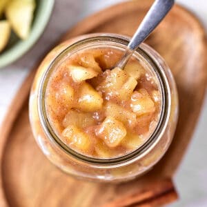 Jar of apple pie filling and topping. Wooden oval tray, silver spoon.
