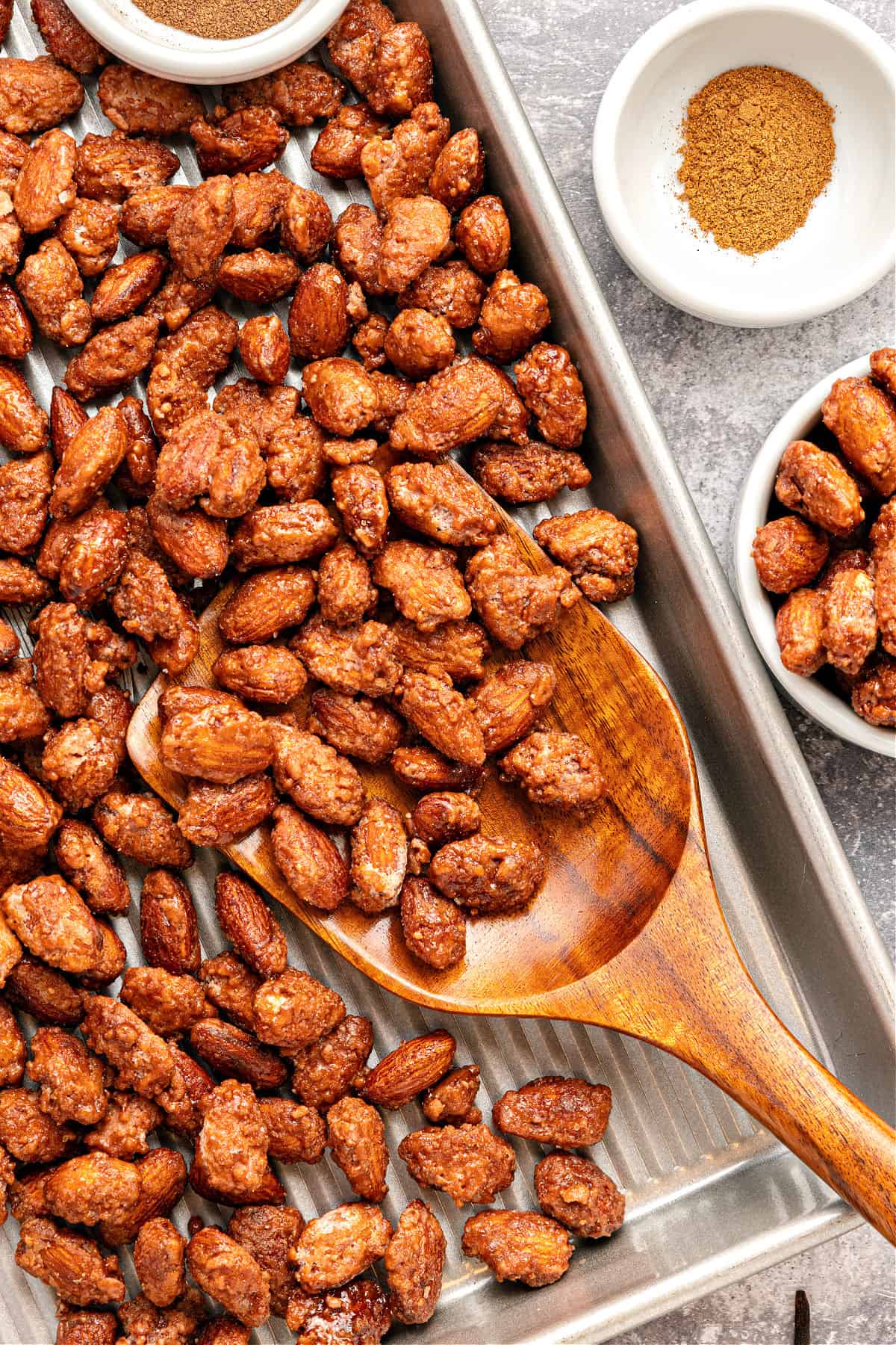 Metal pan with candied almonds and wooden spoon. Bowl with spices.