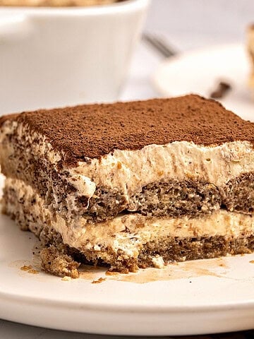 Serving of Italian tiramisu on a white plate. White background.