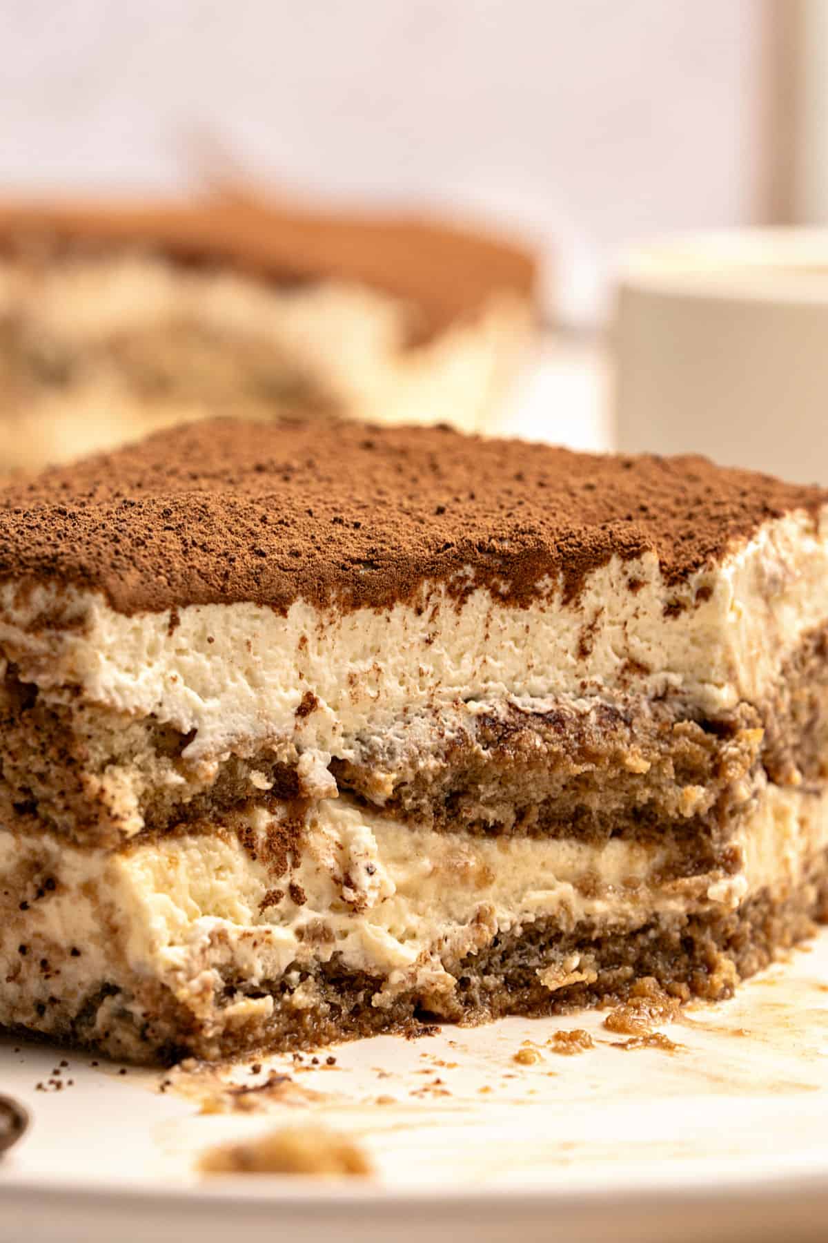 Close up cut square of chocolate-topped tiramisu. White plate.