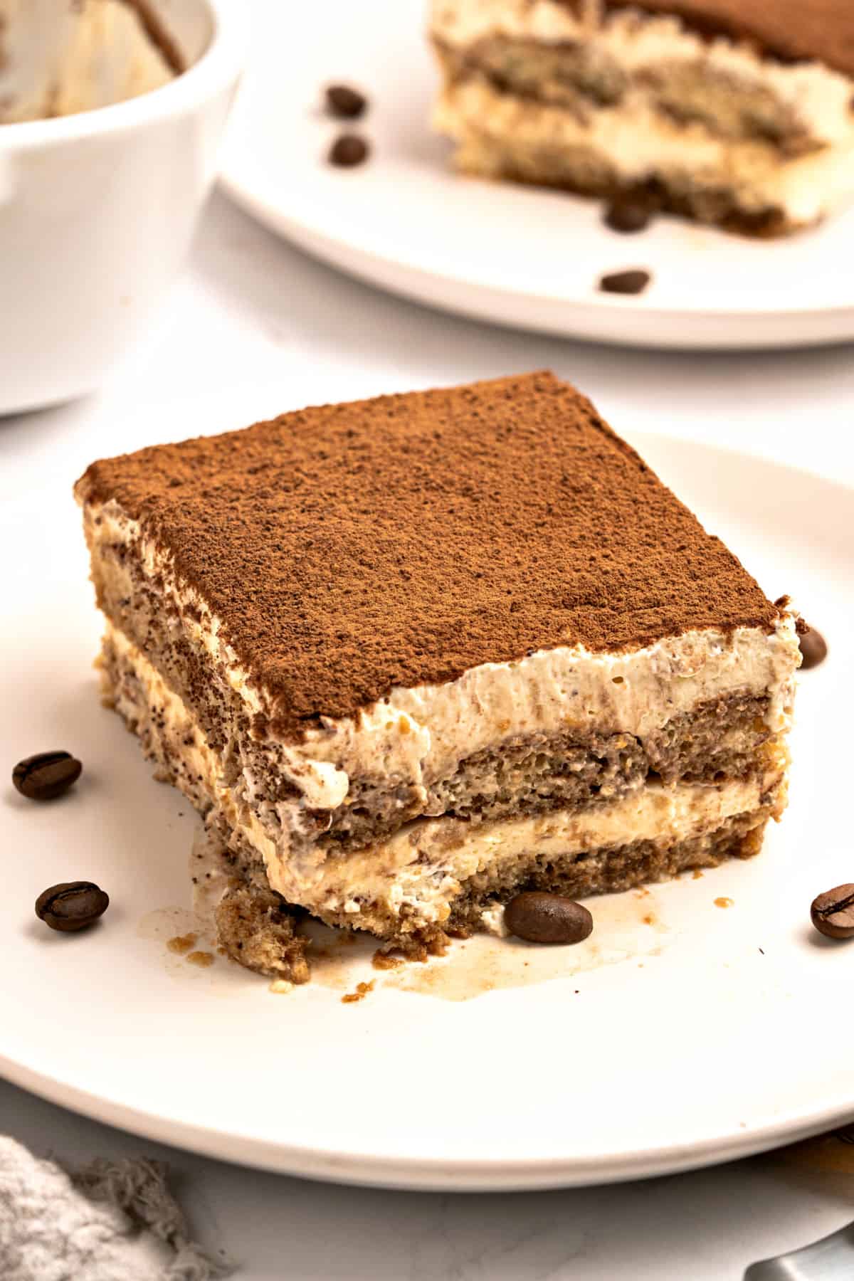 Chocotorta Square of cacao-topped tiramisu on a white plate. Coffee beans.