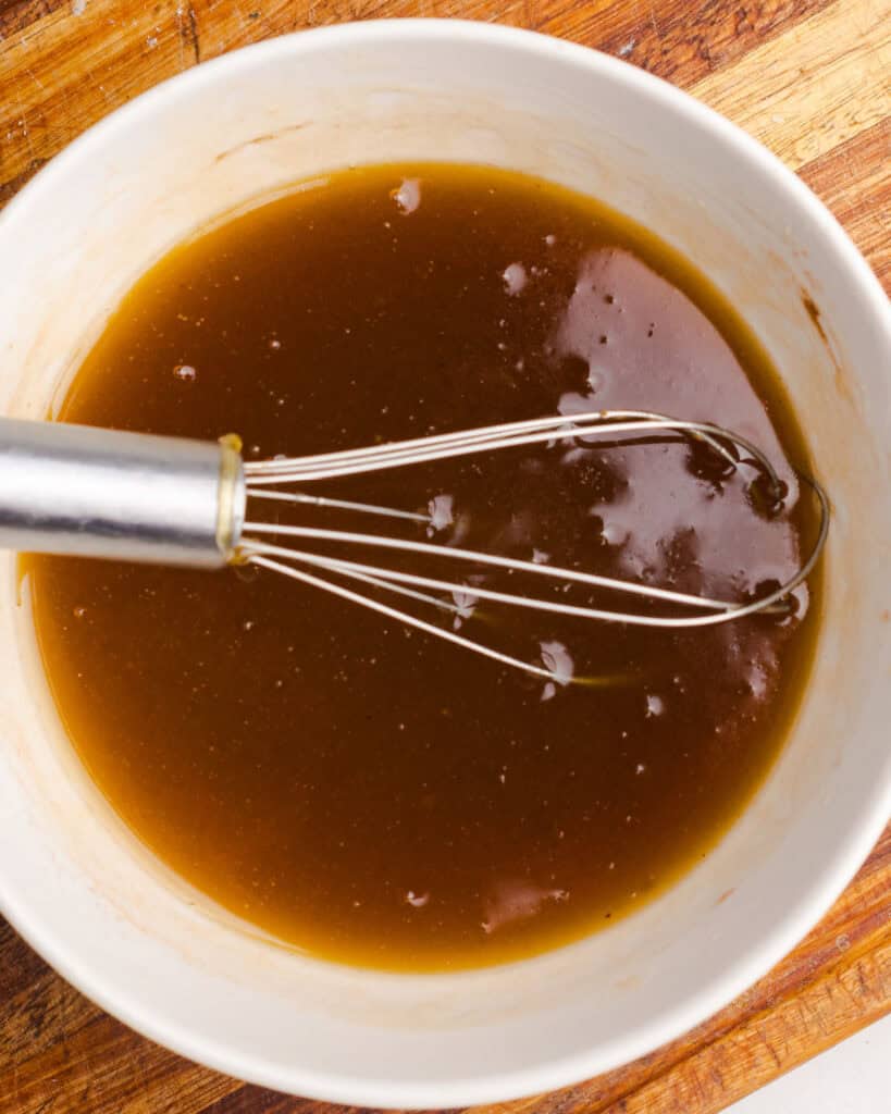 White bowl with honey butter mixture. Silver whisk.