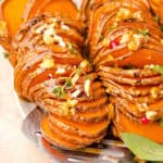 Close up hasselback honey roasted sweet potatoes with chopped walnuts.