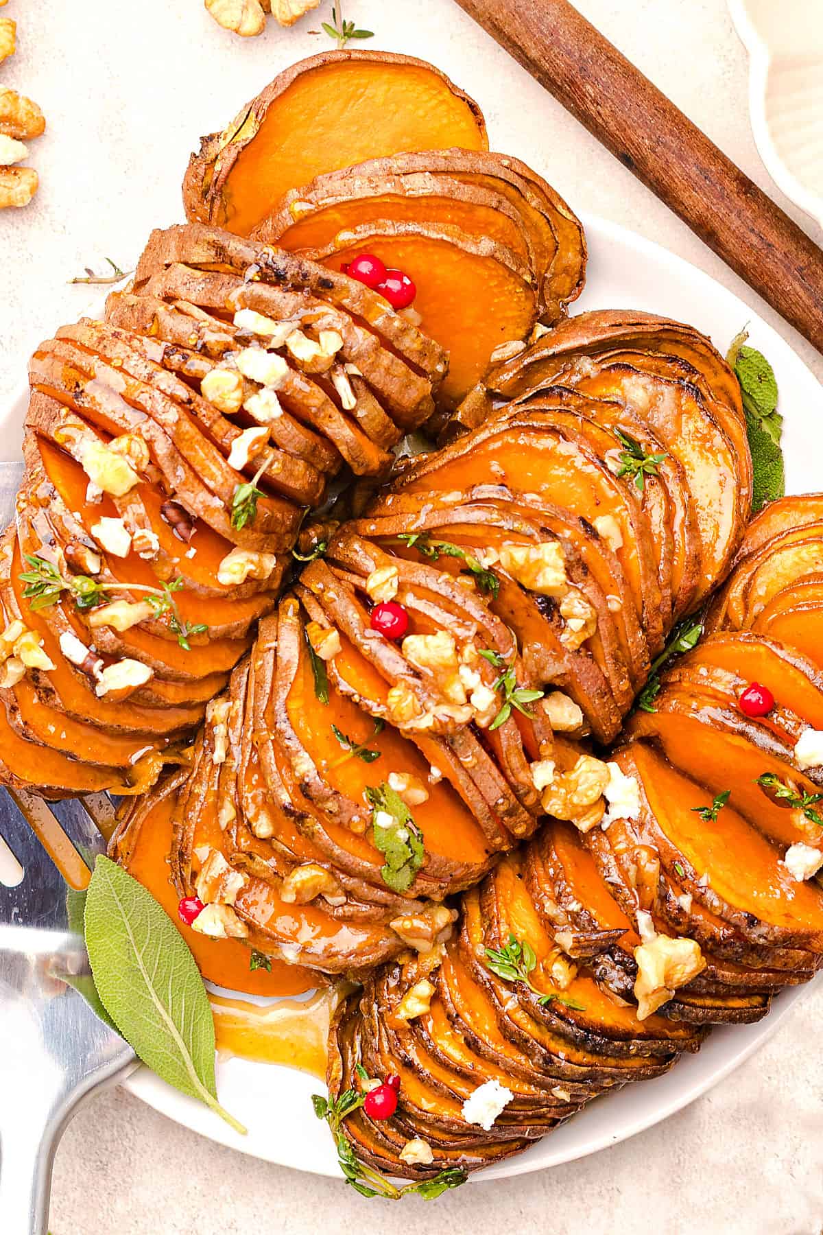 Top view of white platter with hasselback honey roasted sweet potatoes with chopped walnuts.