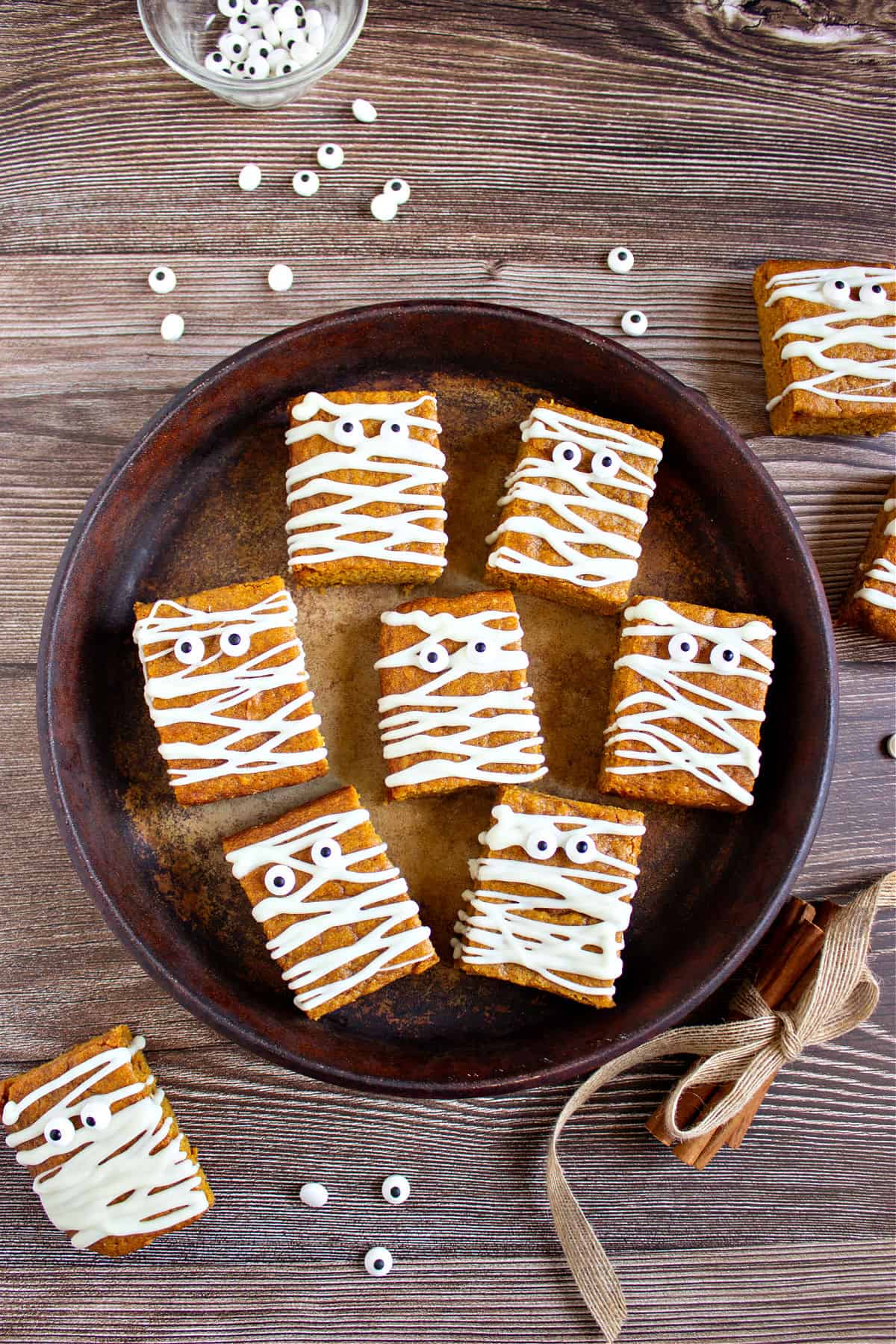 Brown tray and background with pumpkin mummy blondies. Candy eyes.