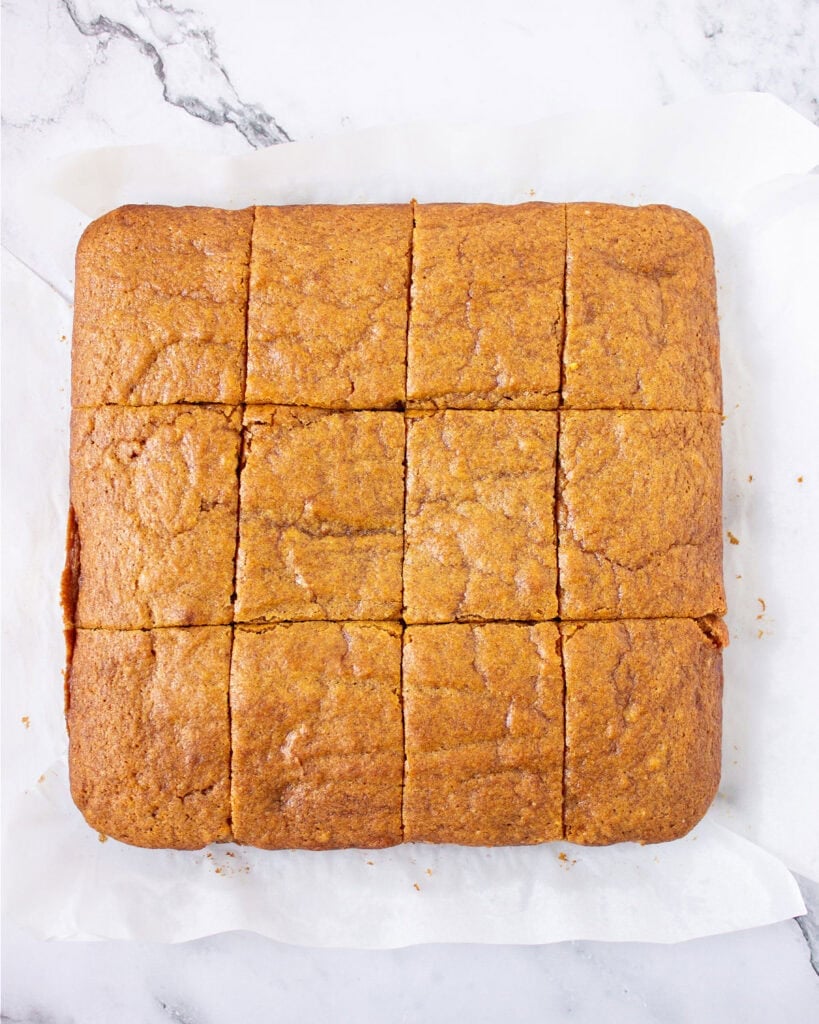 Marbled surface with parchment and cut pumpkin blondies on top.