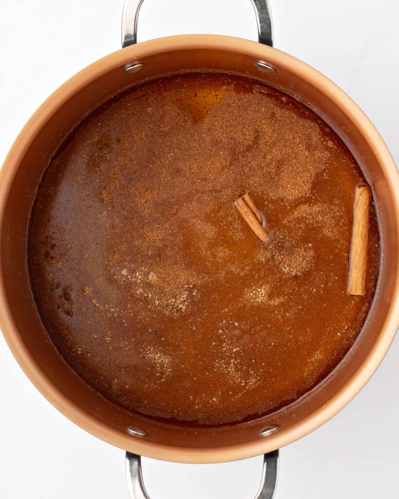 Ingredients for wassail apple drink in a copper pot with handles. 