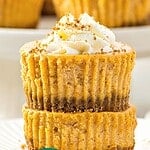 Teal, white and brown text overlay on stack of mini pumpkin cheesecakes.