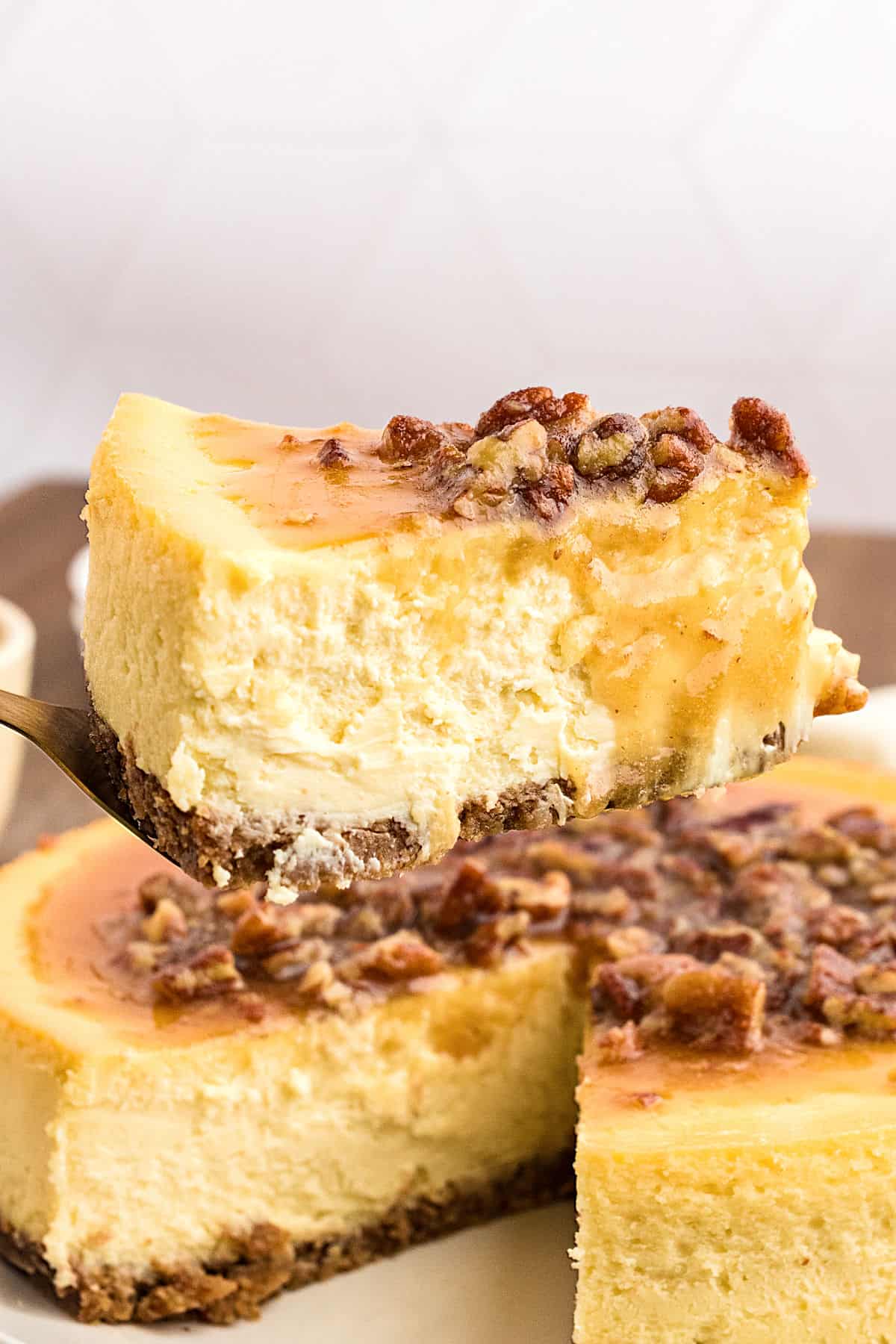 Lifting a slice of pecan pie cheesecake from whole cake.