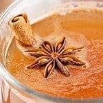 Glass mug with apple cider, cinnamon stick and star anise.