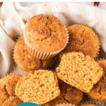 Teal, brown and white text overlay on pile of whole and halved muffins.
