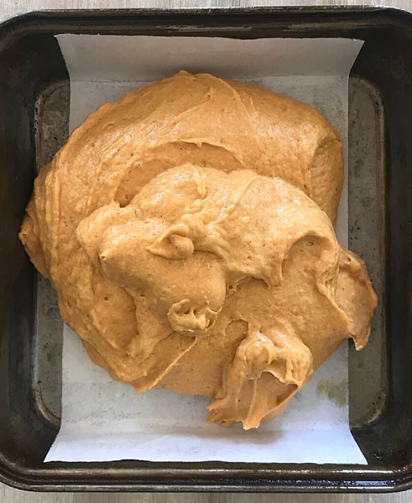 Lined rectangular metal pan with pumpkin blondie batter.