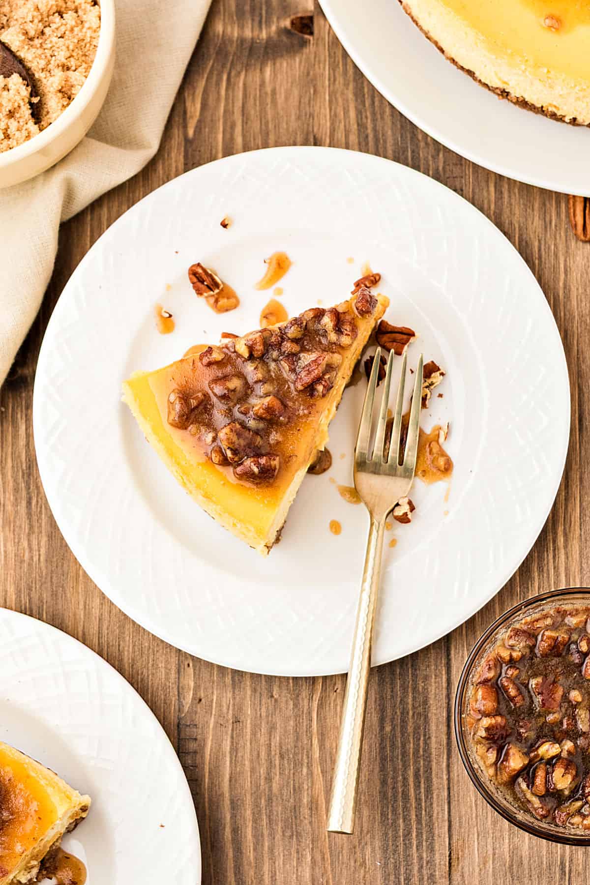 Top view of white plate with maple pecan cheesecake slice. Silver fork. Wooden background. 