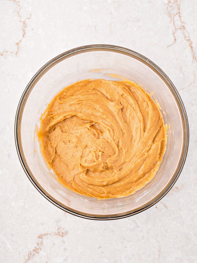 Batter for sweet potato muffin in a glass bowl. Marbled surface.
