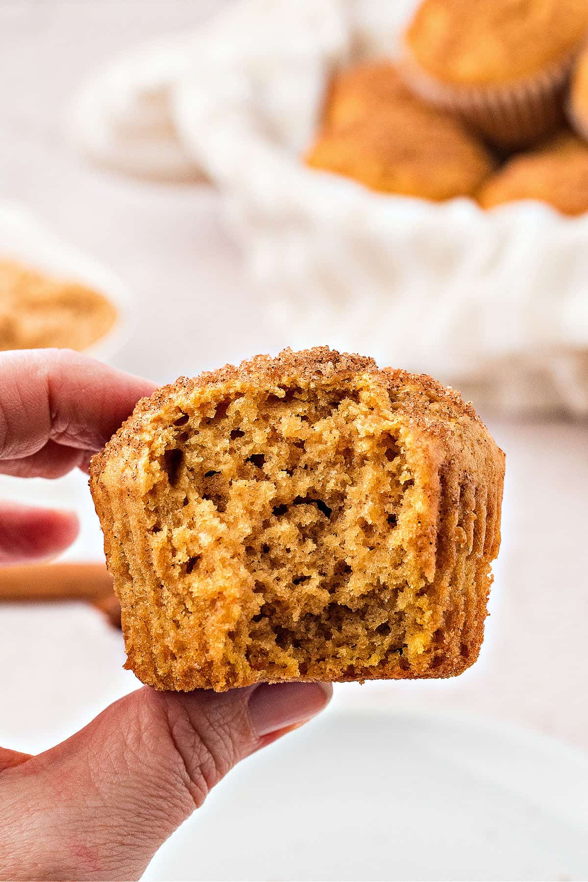Holding a bitten sweet potato muffin over a white background.