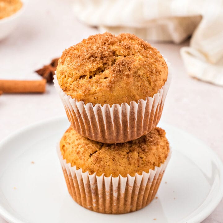 Stack of two sweet potato muffins in paper liners. White plate and background.
