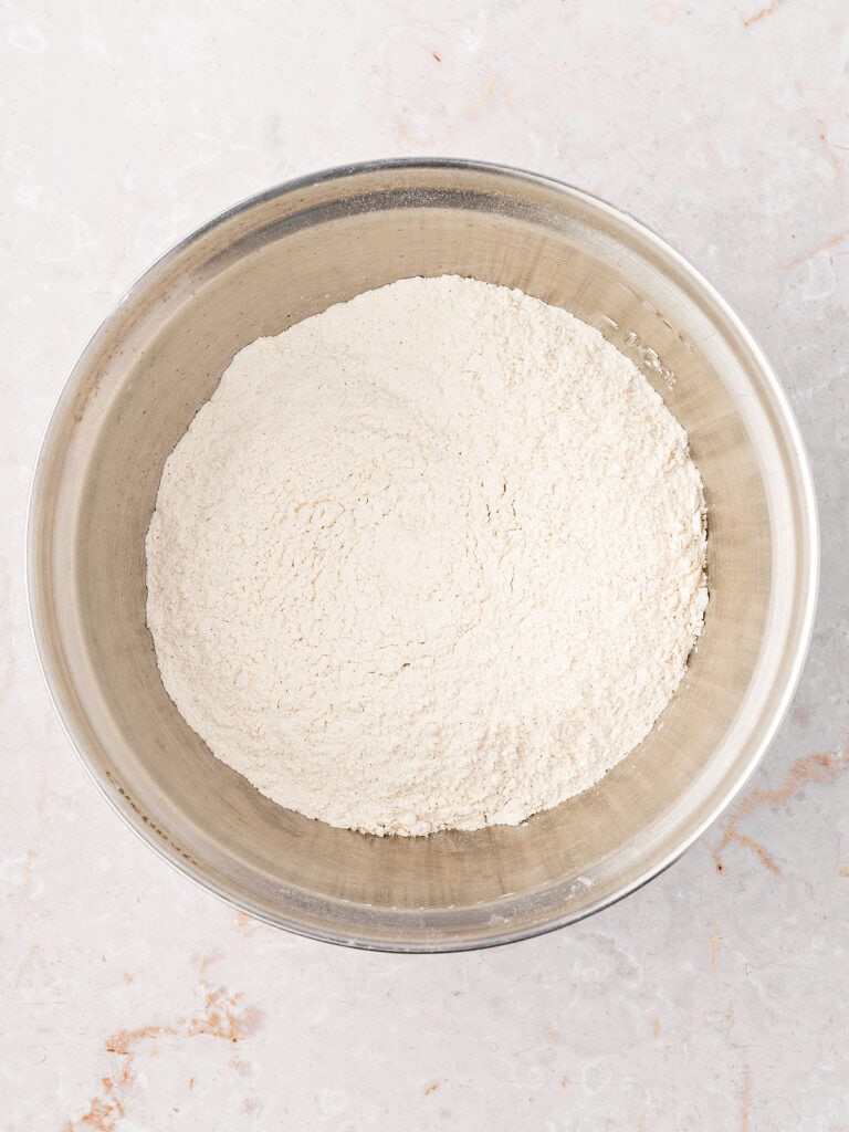 Metal bowl with dry ingredients for muffins. White marbled background.