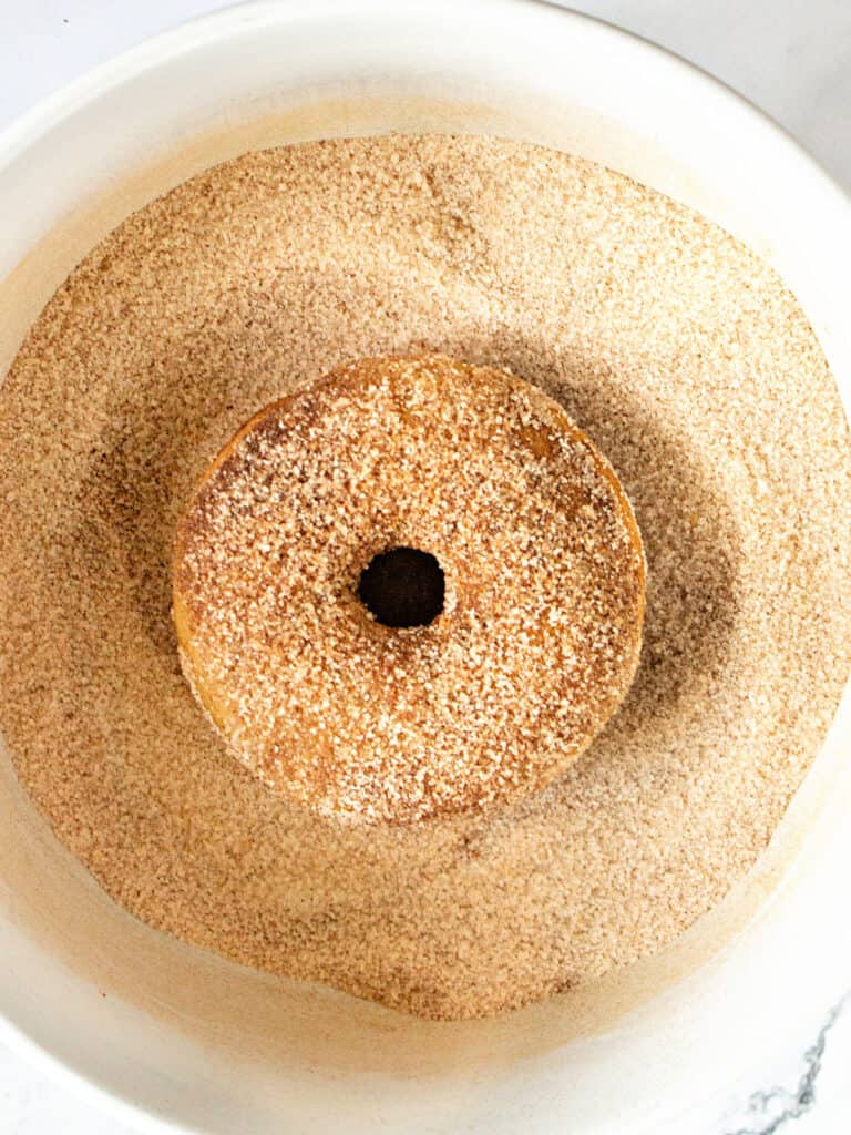 Rolled baked donut in cinnamon sugar. White bowl.