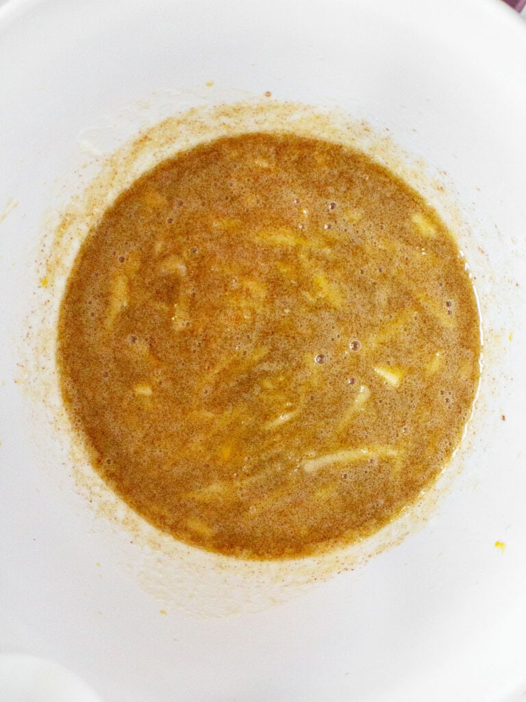 White bowl with wet ingredients for apple cider donuts.