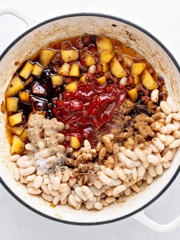 Black-rimmed white pot with beans, apples, ketchup and molasses. Top view.