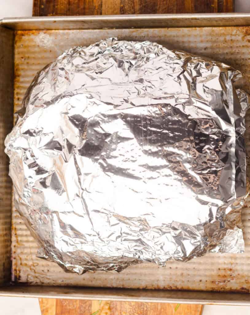 Foil-wrapped bread loaf on a metal square baking pan.
