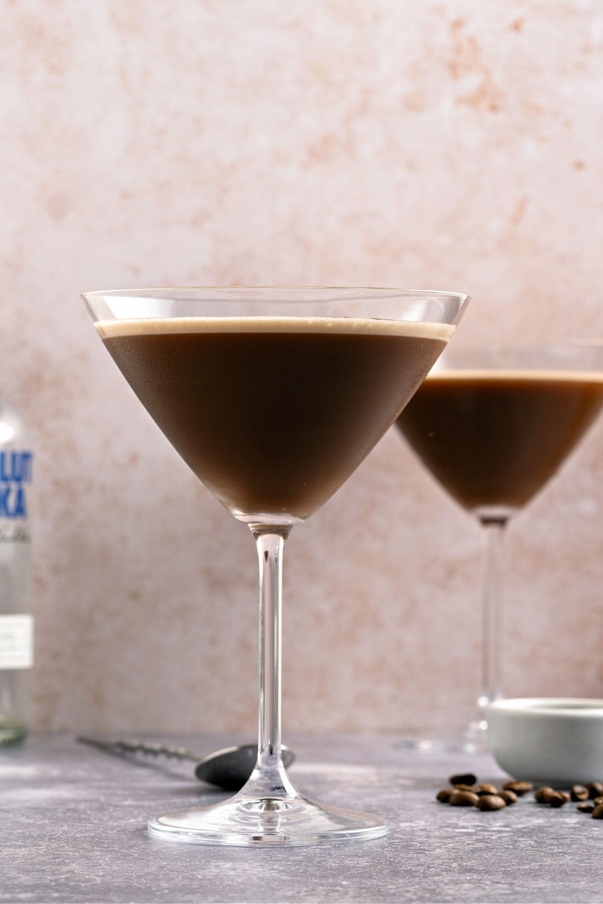 Front view of two chocolate martini stem glasses. Reddish background.