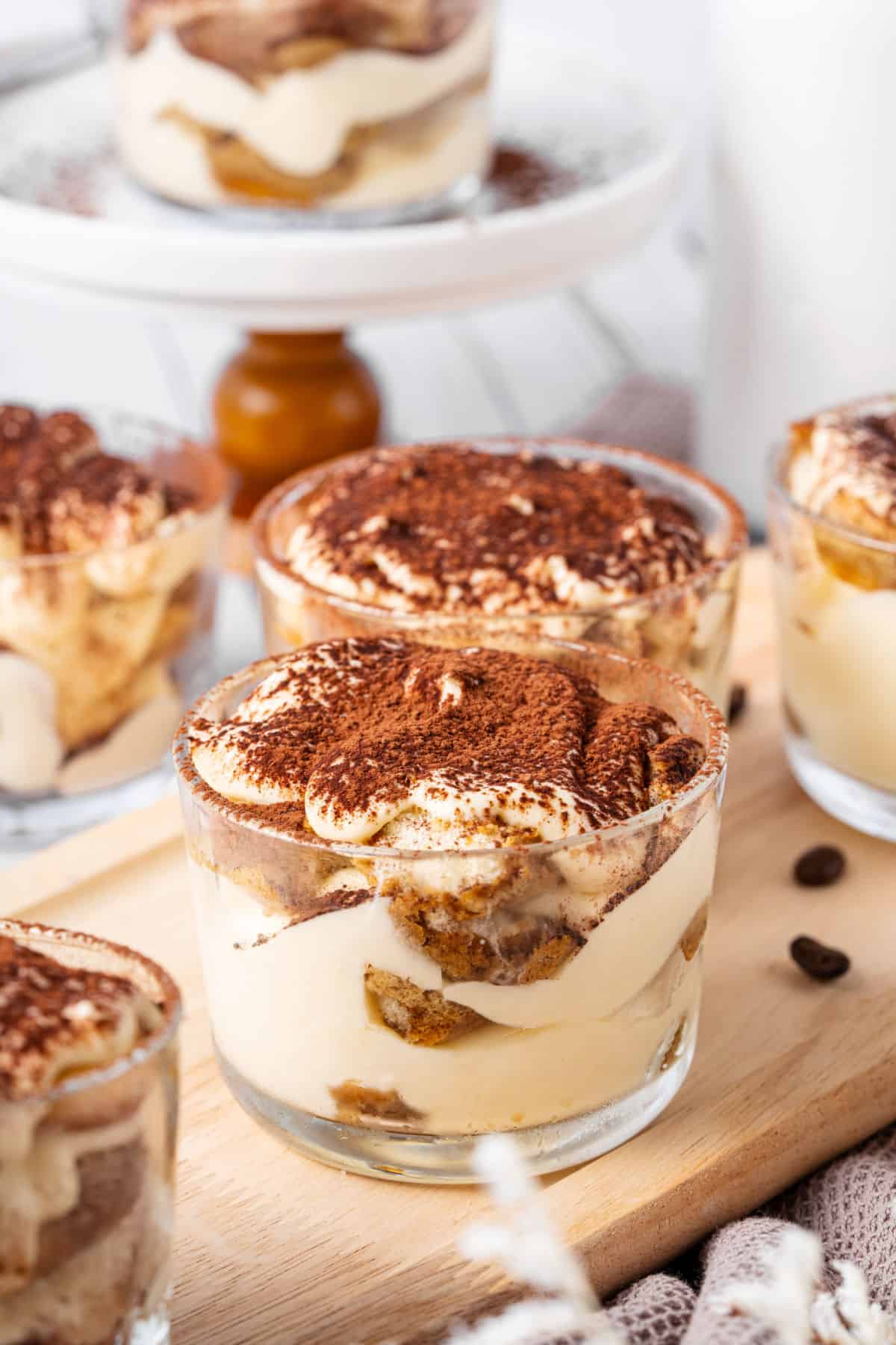 Cocoa dusted tiramisu glasses. White background, cake stand, more cups.