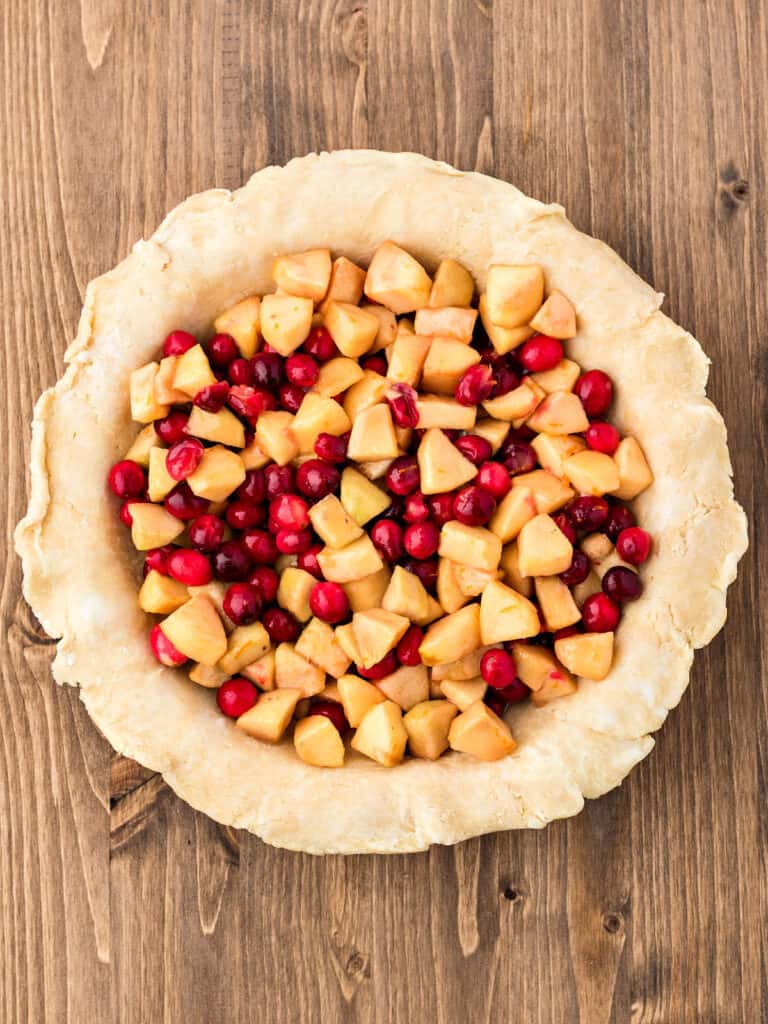 Unbaked pie crust with cran apple filling. Wooden surface. Top view.