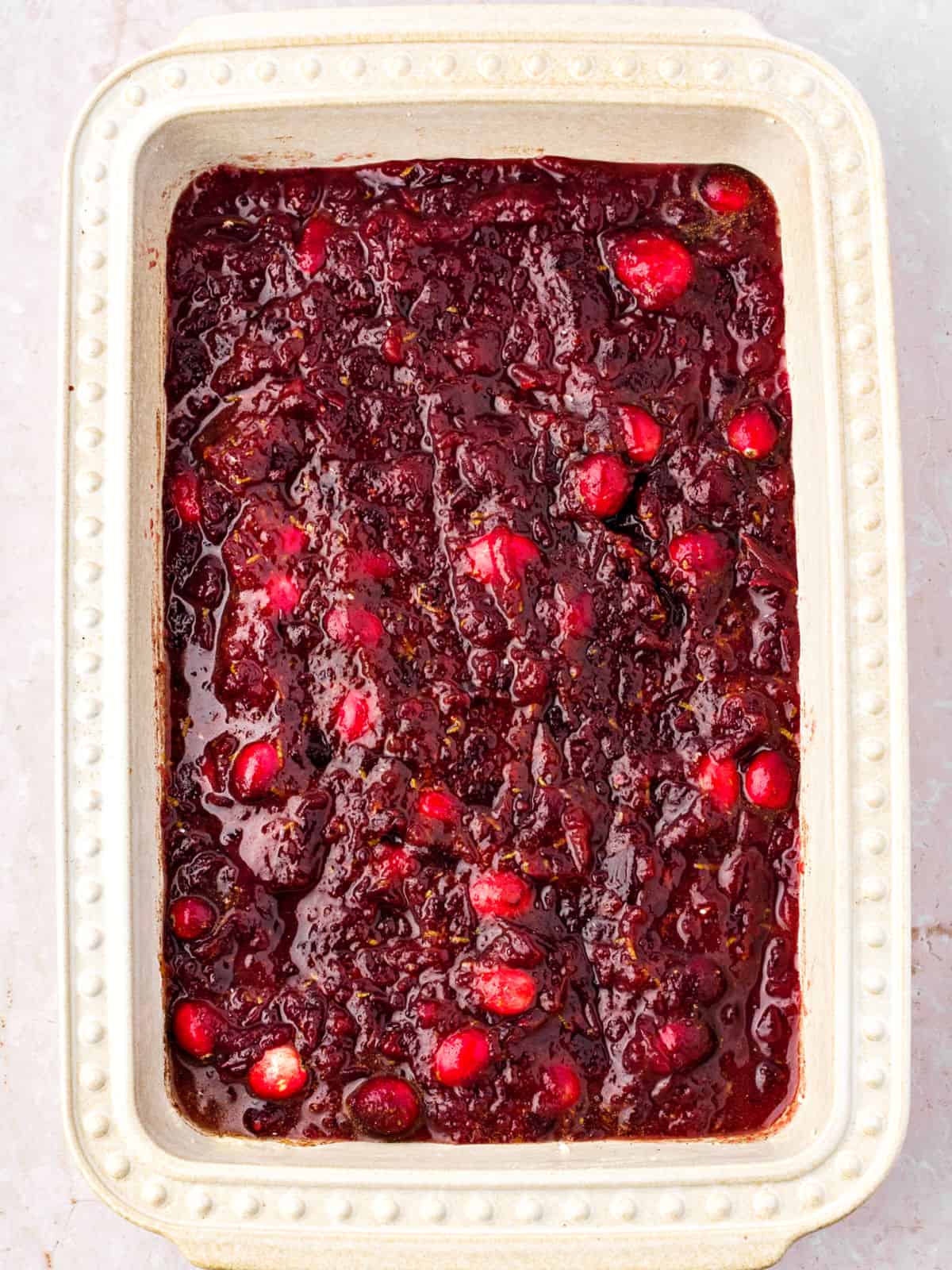 Filling for cranberry cobbler in a rectangular cream-colored dish.