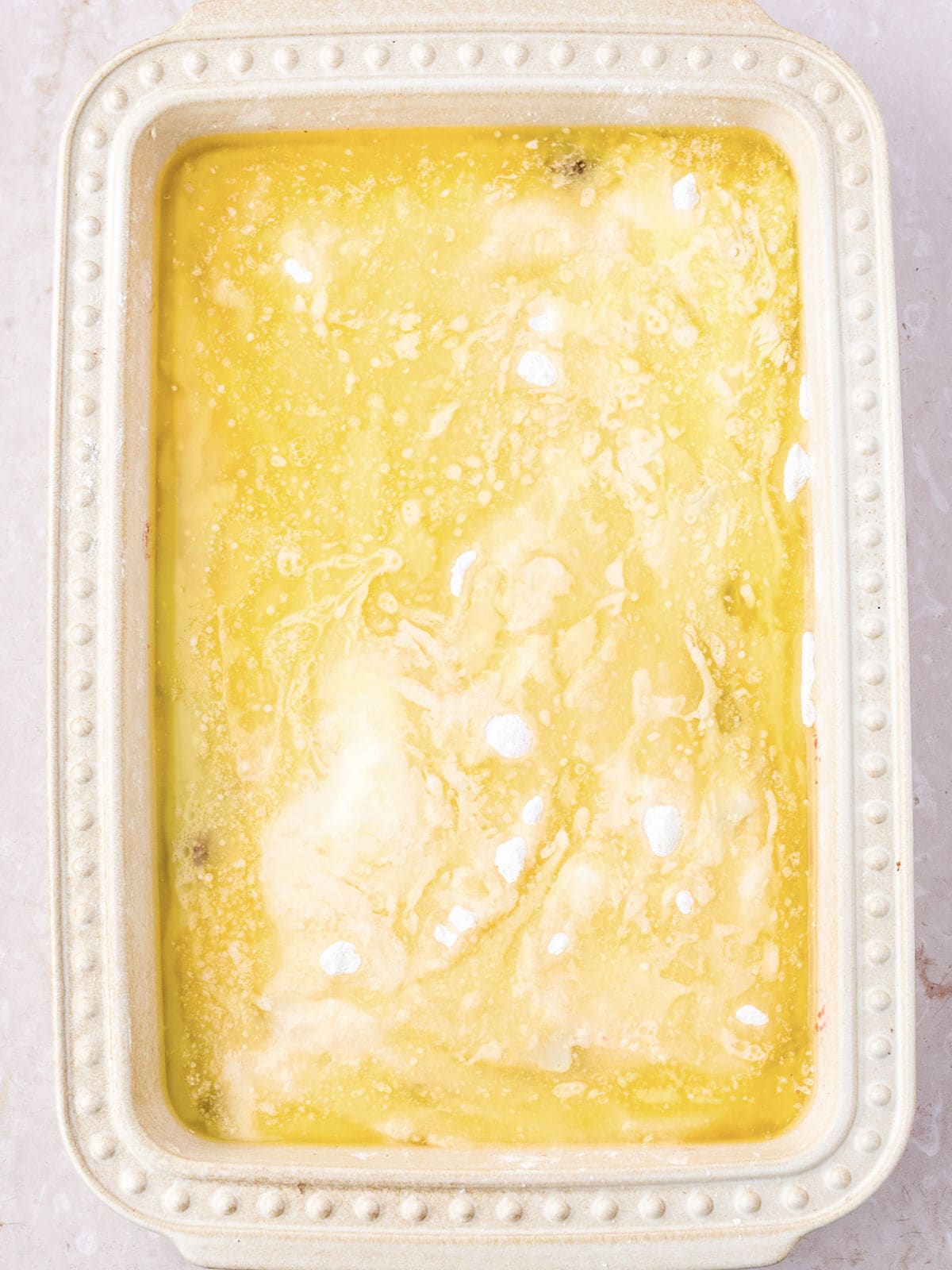 Melted butter topping in a cream-colored rectangular baking dish.