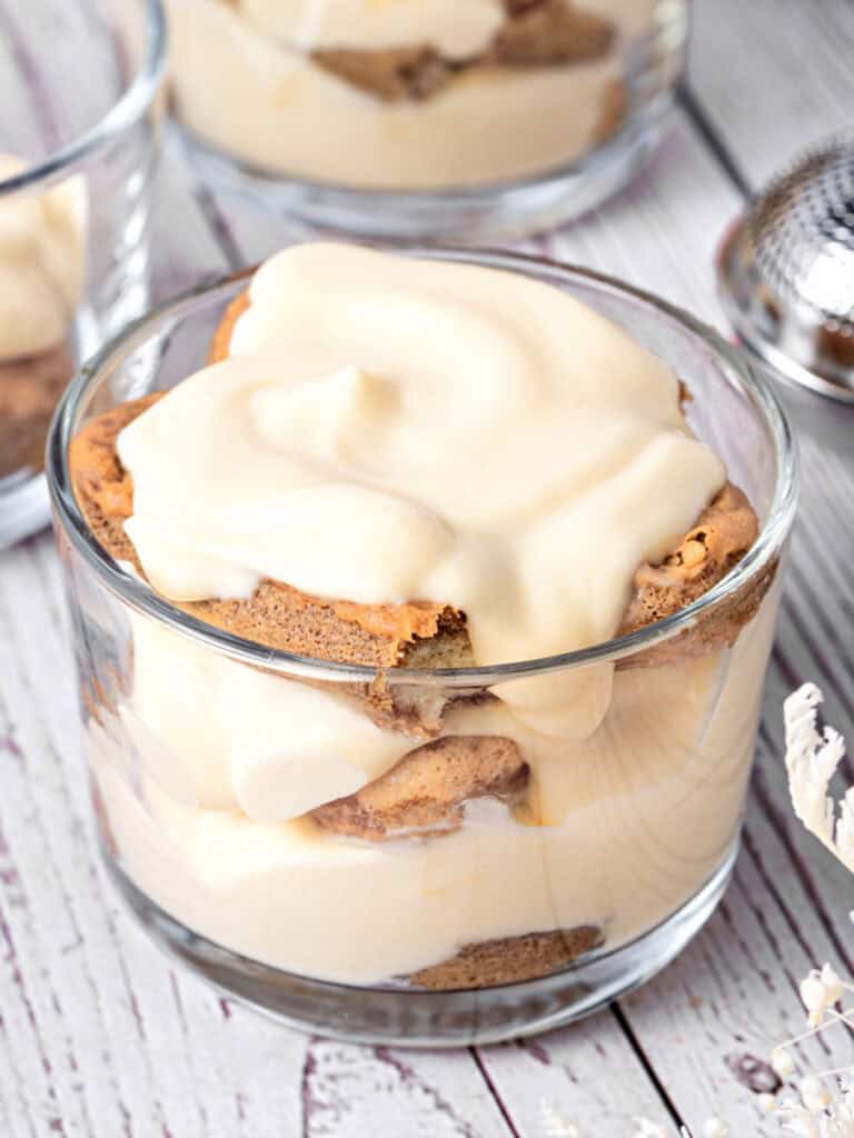 Vintage white wooden surface with glass of tiramisu in a glass.
