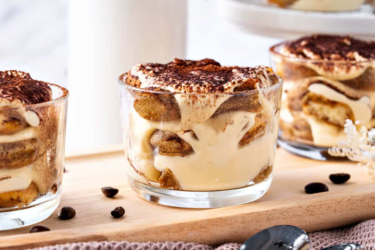 Light wooden board with tiramisu glasses.