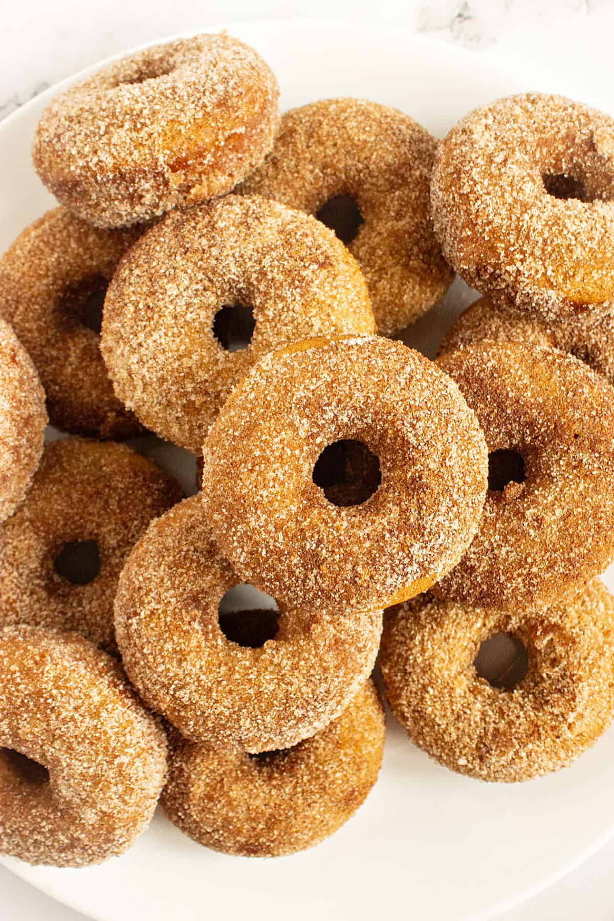 Pile of cinnamon sugar coated donuts. White background.