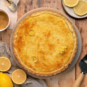 Whole ricotta pie, wooden surface, lemon slices.