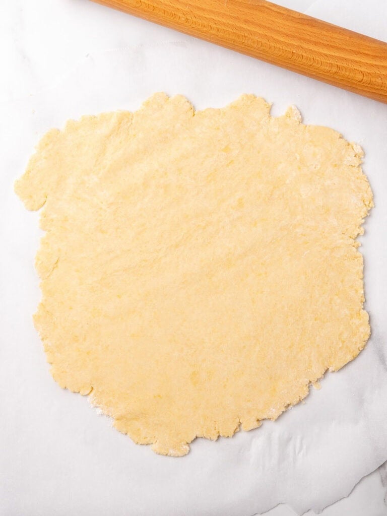 Rolled pie crust on white marble. Rolling pin.
