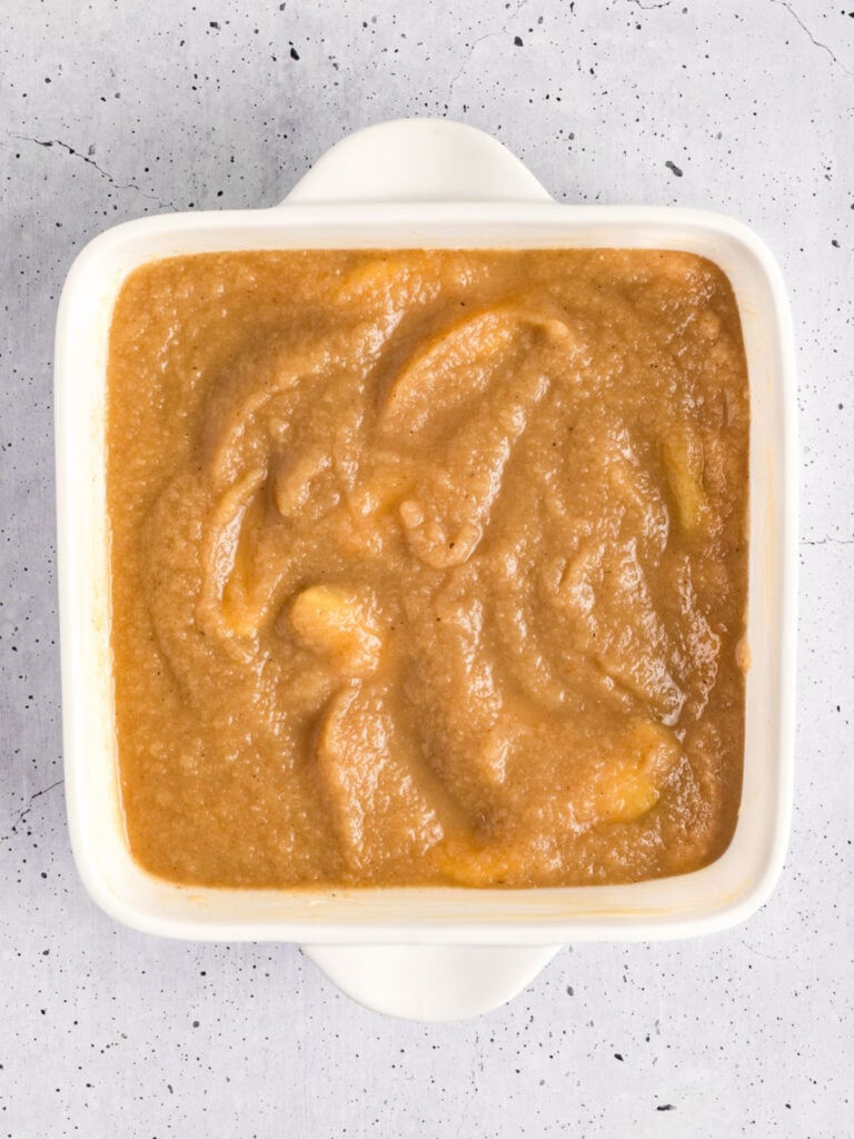 White square dish with applesauce filling. Light gray background.