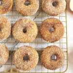 Three rows of apple cider donuts with cinnamon sugar coating on a wire rack.