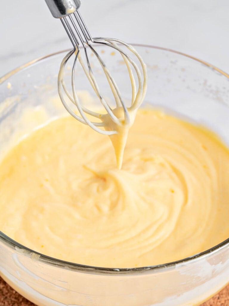 Thick custard with mascarpone in a glass bowl. Balloon whisk.