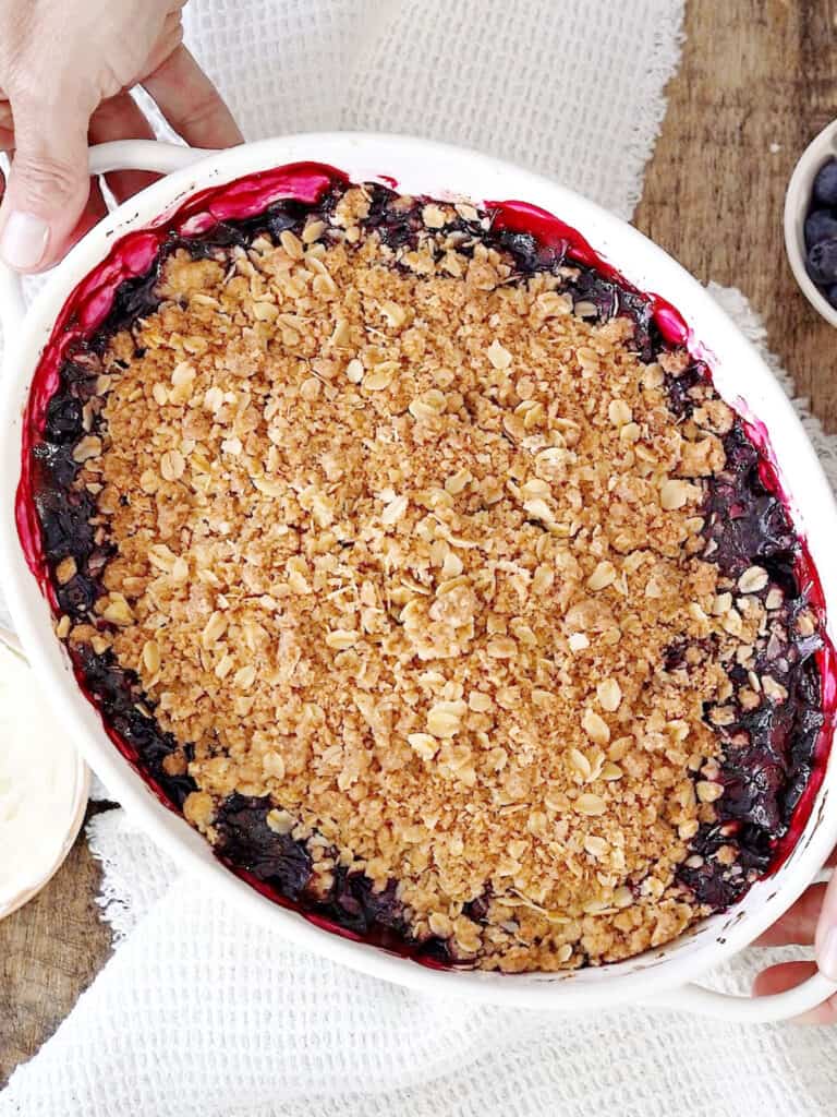 White oval dish with baked blueberry oat crisp.