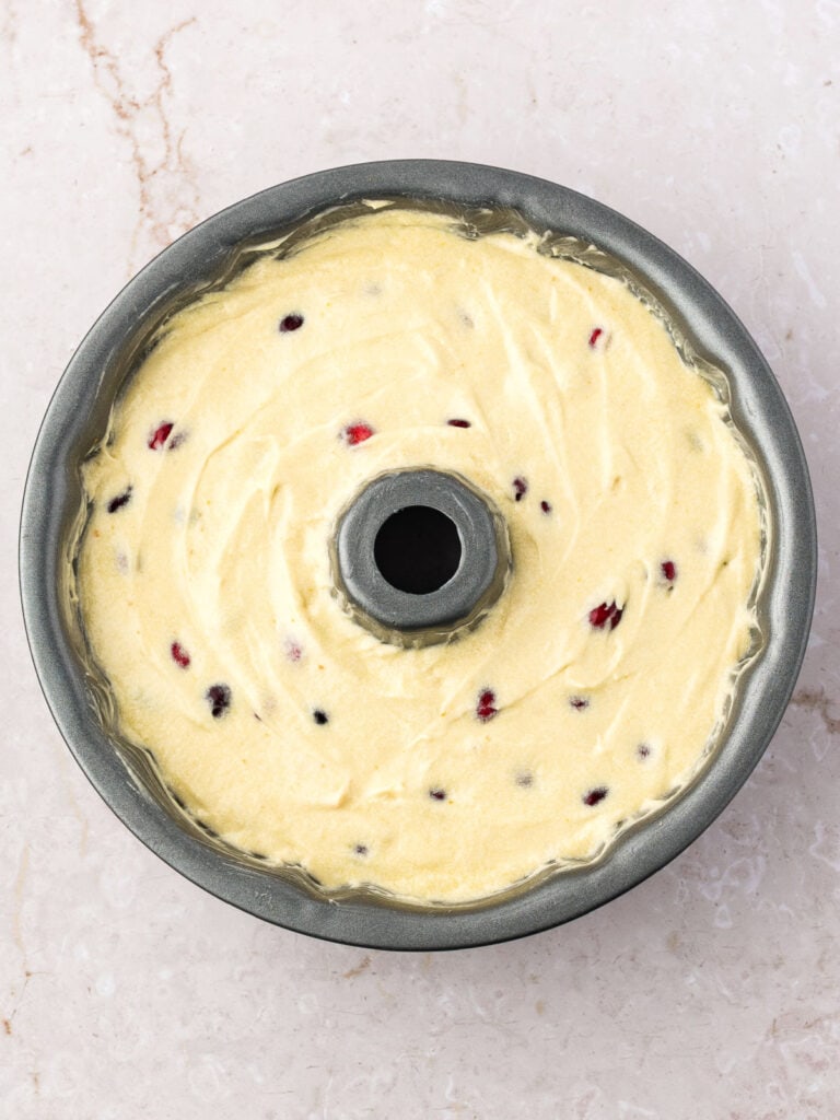 Bundt cake pan with cranberry pound cake batter. Marbled background.
