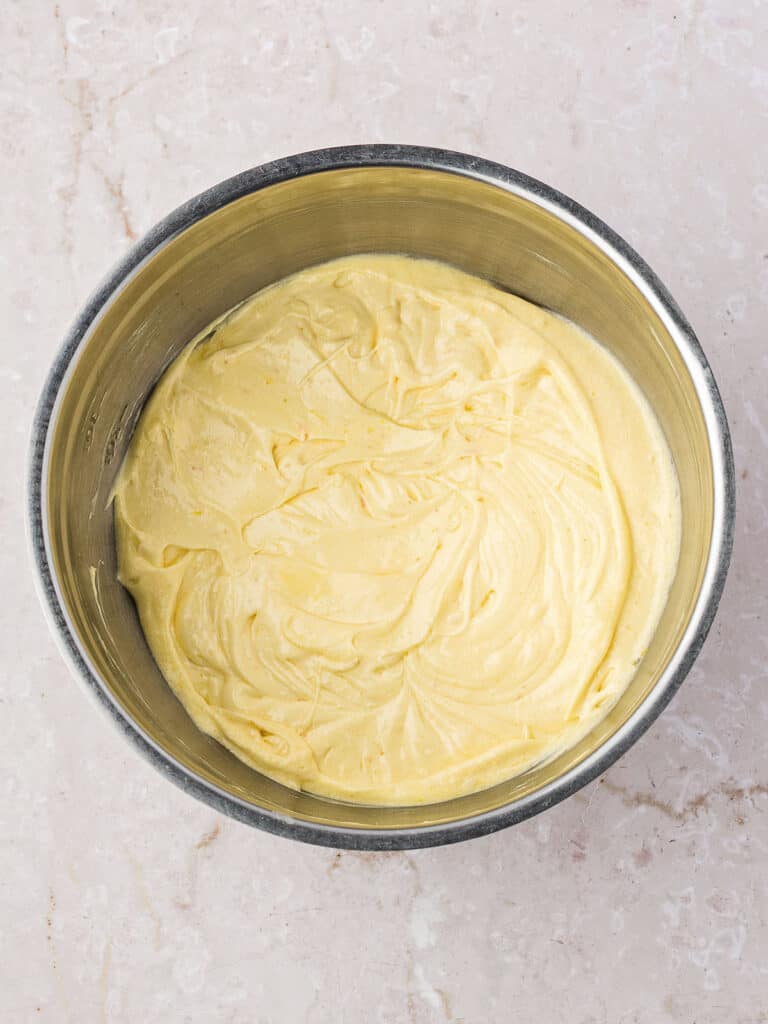 Metal bowl with bundt cake batter. Marbled background. 