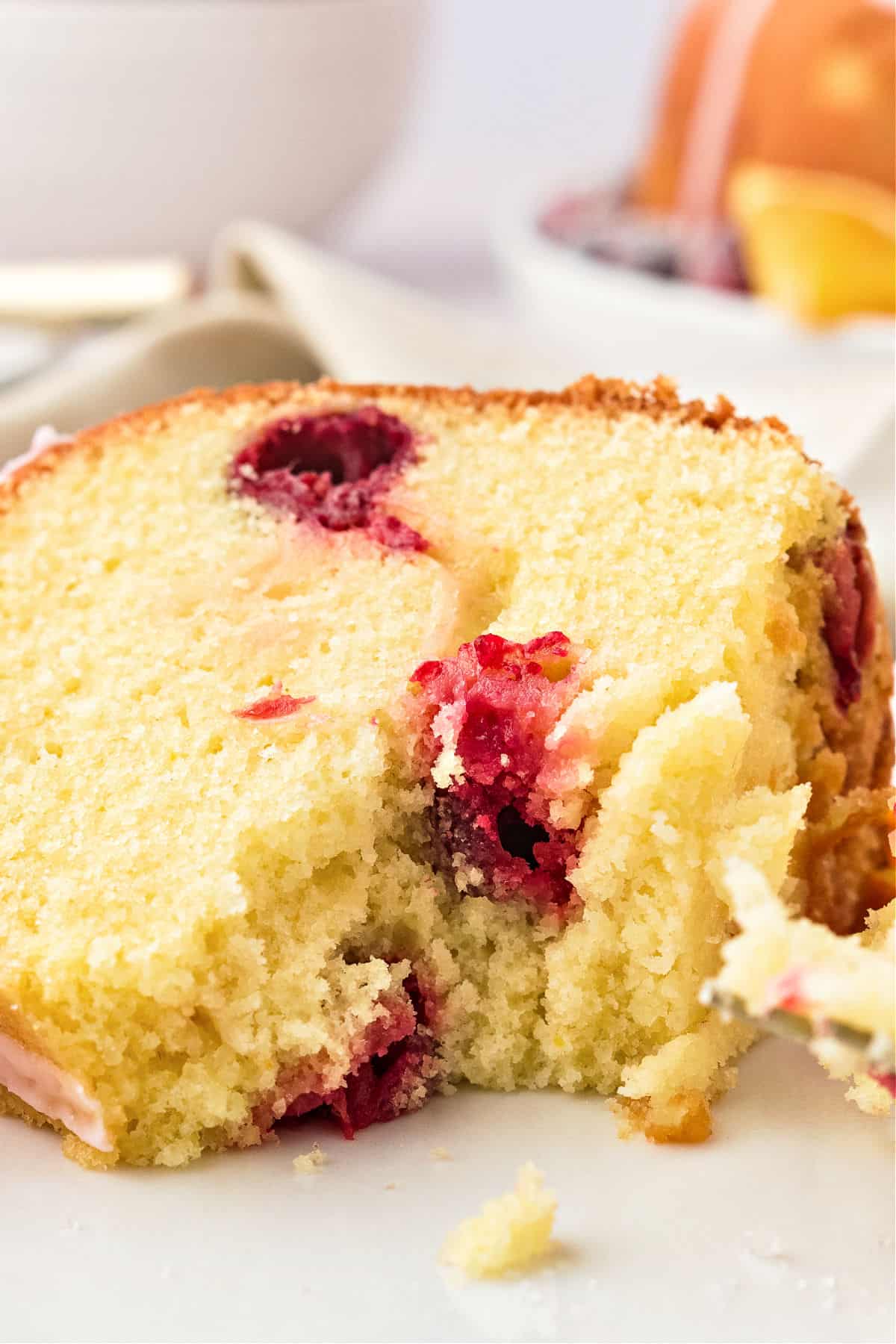 Close up forked slice of cranberry bundt cake. White plate.