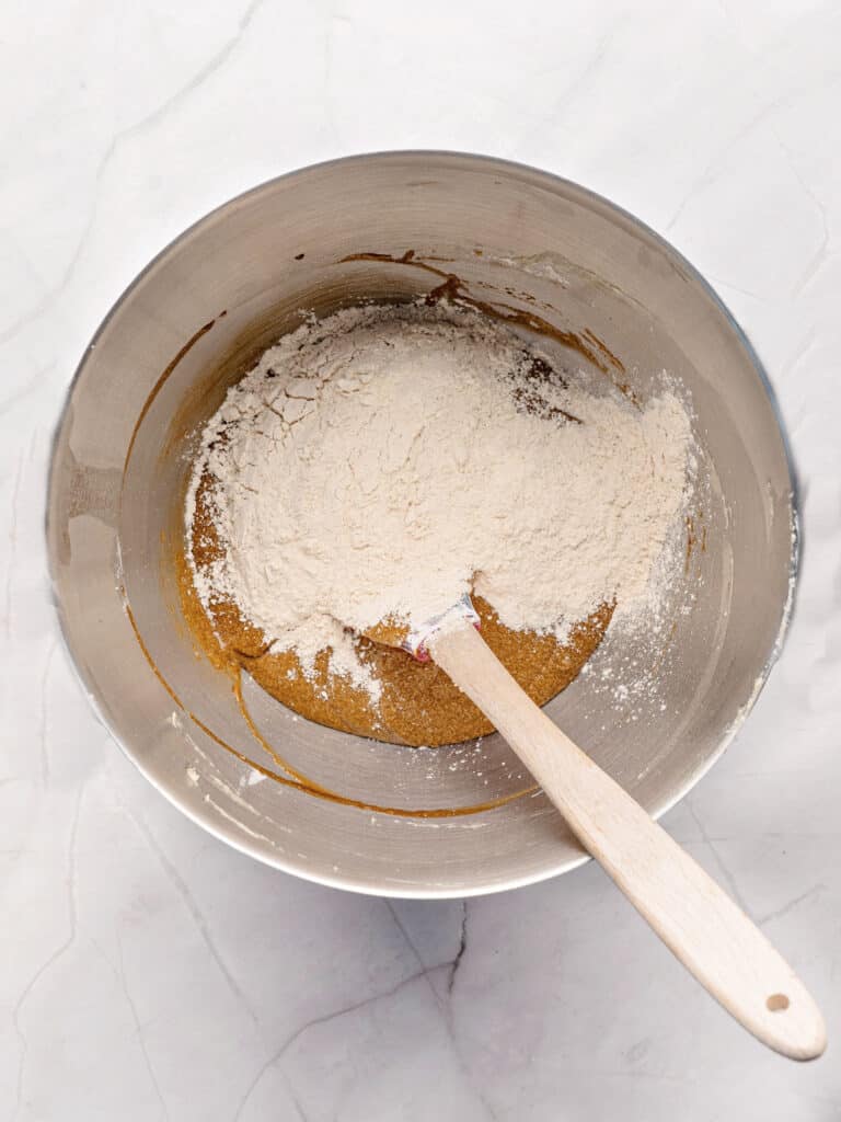 Metal bowl with spatula, flour and gingerbread cake batter. White background.