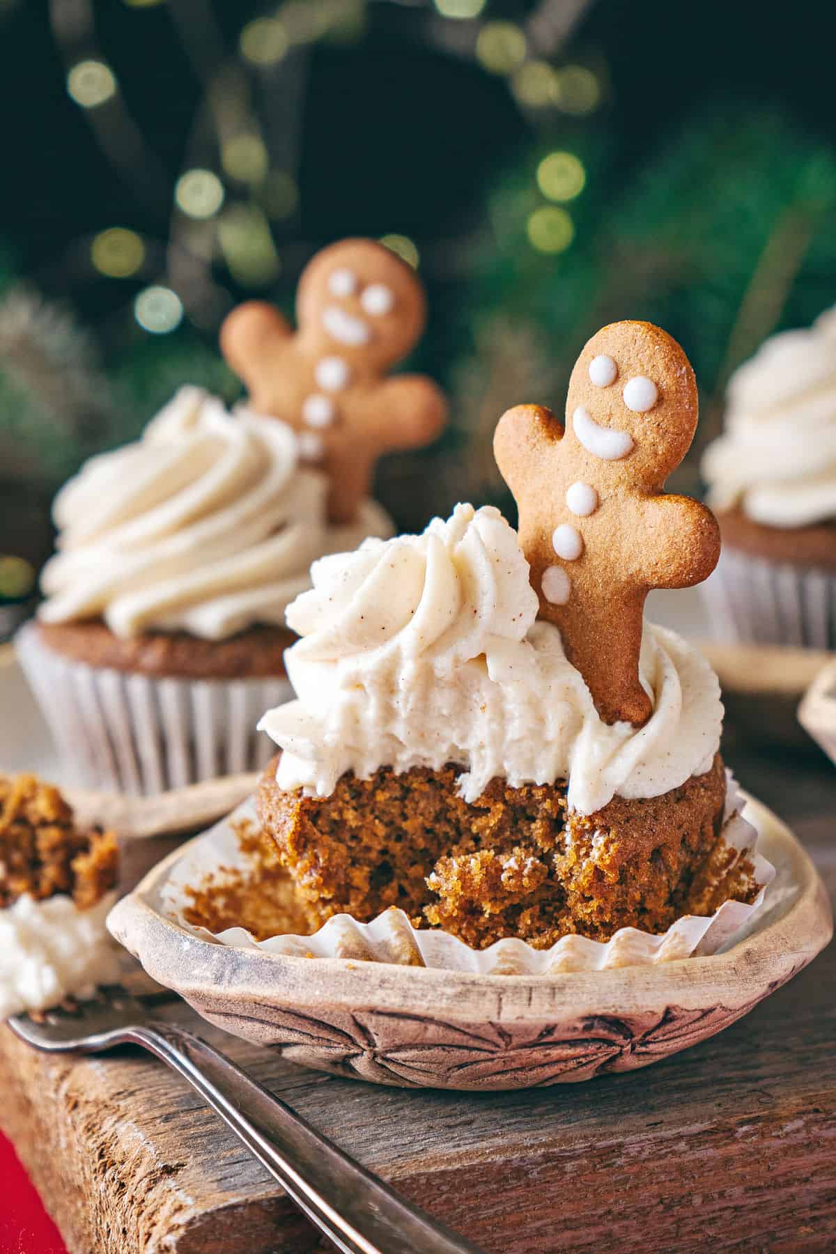 Forked frosted gingerbread cupcake with cookie decoration. Wood and green background.