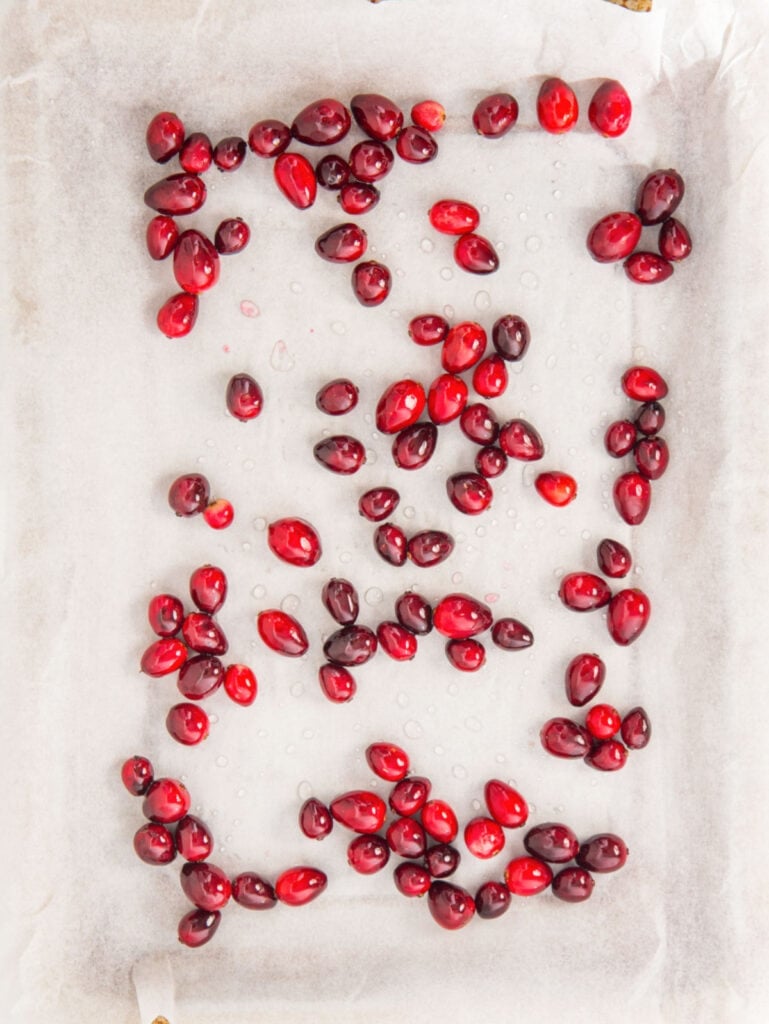 Drying syrup coated cranberries on white parchment paper.
